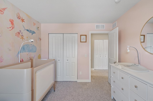 bedroom with baseboards, visible vents, a closet, and light colored carpet