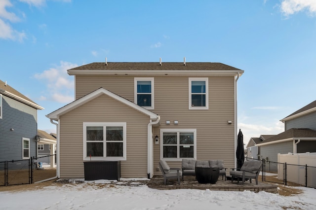 snow covered back of property with a gate, a patio area, fence, and an outdoor living space