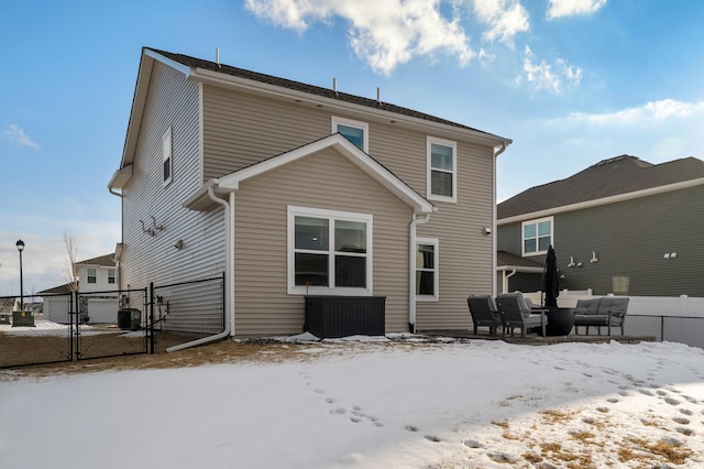 snow covered property featuring a gate, outdoor lounge area, and fence