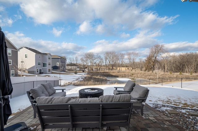 snow covered patio featuring an outdoor living space with a fire pit, a residential view, and fence