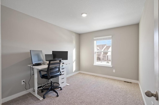 carpeted office space with visible vents, a textured ceiling, and baseboards