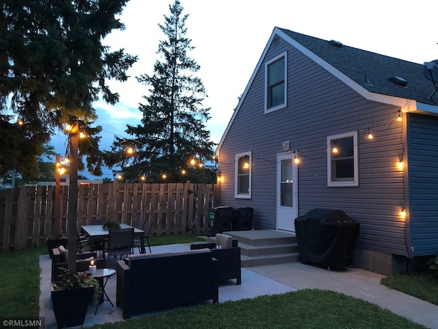 rear view of property featuring a shingled roof, outdoor lounge area, a patio, and fence