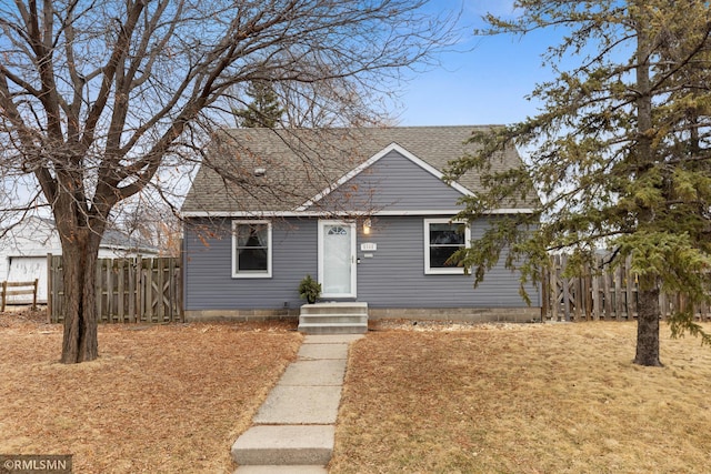 bungalow-style home featuring a shingled roof and fence