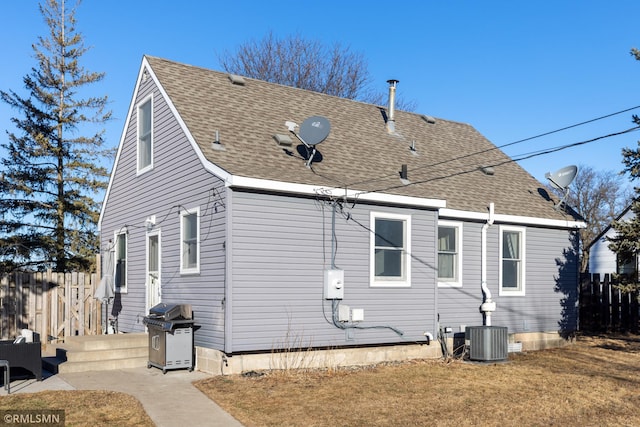 exterior space with a shingled roof, cooling unit, a yard, and fence