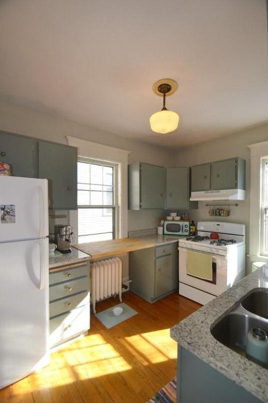 28 Saint Albans St N Unit 4N, Saint Paul, MN 55104 - kitchen featuring white appliances, radiator heating unit, gray cabinets, under cabinet range hood, and light wood-style floors