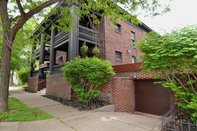 28 Saint Albans St N Unit 4N, Saint Paul, MN 55104 - view of property exterior with brick siding, concrete driveway, stairway, an attached garage, and a balcony