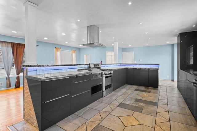 kitchen with recessed lighting, stainless steel gas stove, island range hood, and modern cabinets