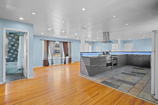 kitchen with recessed lighting, island range hood, light wood finished floors, stainless steel range, and modern cabinets