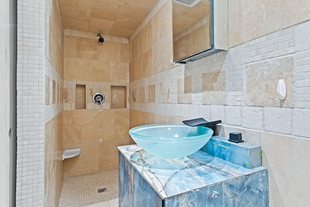 full bath with tiled shower and tile walls