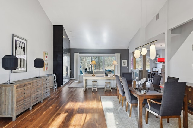 dining room with high vaulted ceiling and hardwood / wood-style floors