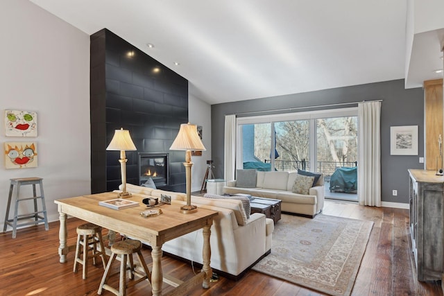 living room featuring a large fireplace, wood-type flooring, an accent wall, and vaulted ceiling