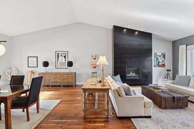 living area with vaulted ceiling, a fireplace, wood finished floors, and baseboards