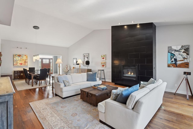 living room with a fireplace, vaulted ceiling, and hardwood / wood-style floors