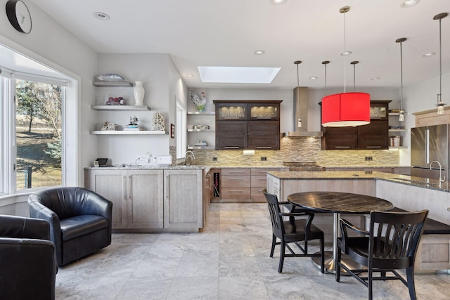 kitchen featuring a skylight, tasteful backsplash, wall chimney exhaust hood, freestanding refrigerator, and open shelves