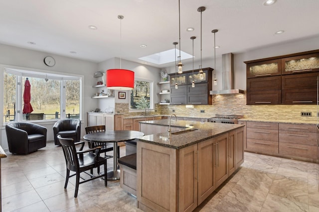 kitchen featuring a skylight, open shelves, tasteful backsplash, plenty of natural light, and wall chimney exhaust hood