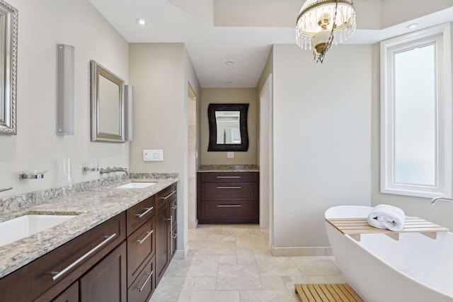 bathroom featuring a sink, a freestanding bath, and double vanity