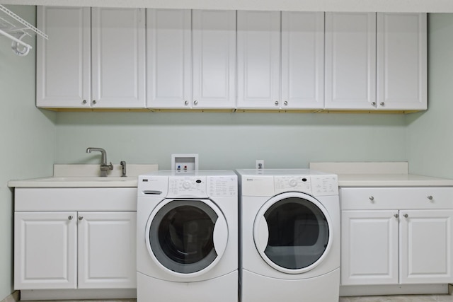 clothes washing area featuring washing machine and dryer, cabinet space, and a sink