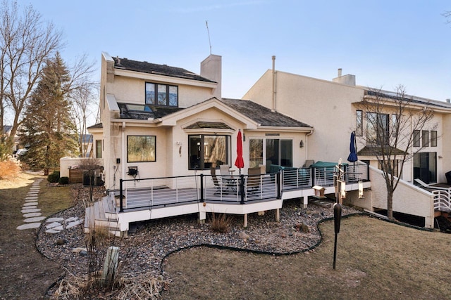 back of property featuring a chimney, a wooden deck, and stucco siding