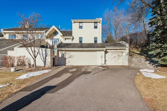 view of front of home featuring aphalt driveway, an attached garage, and stucco siding