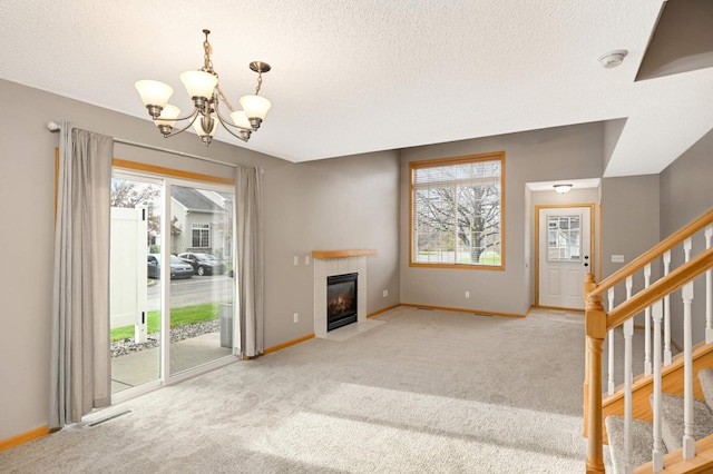 unfurnished living room with baseboards, visible vents, a tiled fireplace, stairway, and carpet floors