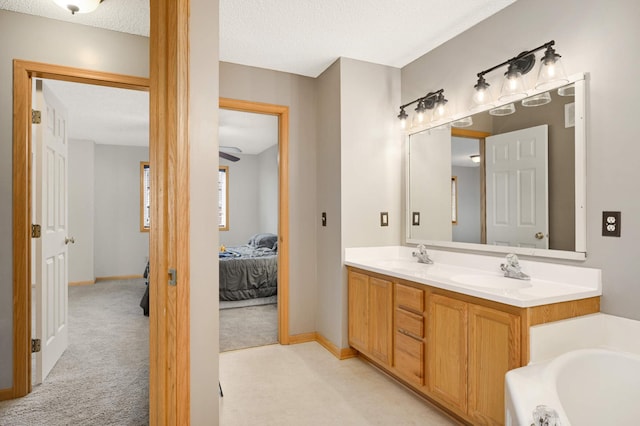 full bath with double vanity, a bathing tub, a sink, a textured ceiling, and ensuite bath