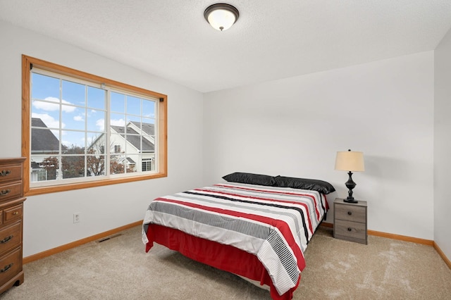 bedroom featuring visible vents, baseboards, a textured ceiling, and light colored carpet