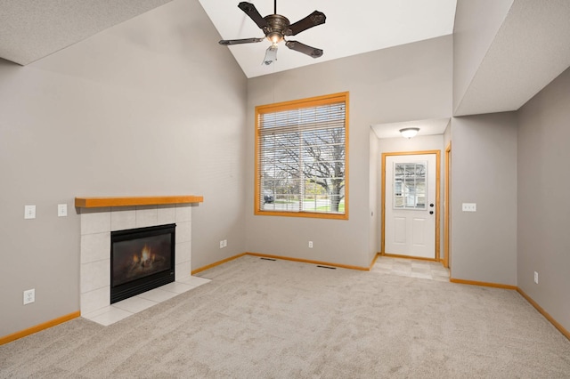 unfurnished living room with light carpet, baseboards, a ceiling fan, a tiled fireplace, and lofted ceiling