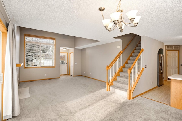 interior space featuring an inviting chandelier, light carpet, a textured ceiling, baseboards, and stairs