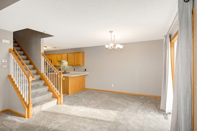 kitchen with light colored carpet, a sink, baseboards, light countertops, and decorative light fixtures