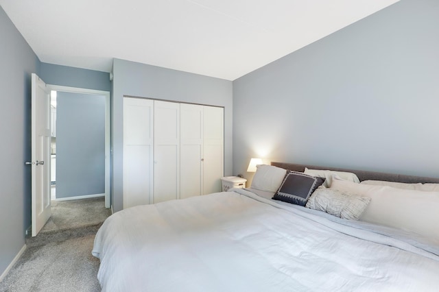 bedroom featuring a closet, light carpet, and baseboards