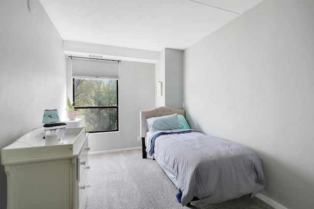 bedroom featuring light colored carpet, a textured ceiling, and baseboards