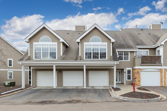 townhome / multi-family property featuring a garage, a balcony, central AC, and driveway