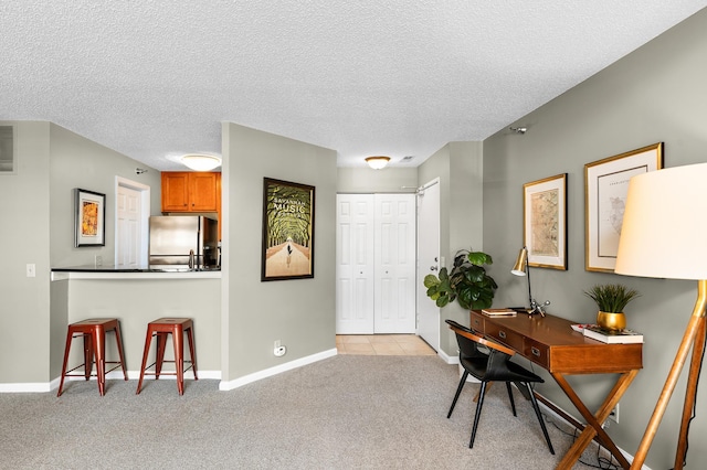 office area with light colored carpet, a textured ceiling, and baseboards