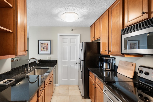 kitchen featuring a sink, dark stone countertops, brown cabinets, appliances with stainless steel finishes, and open shelves