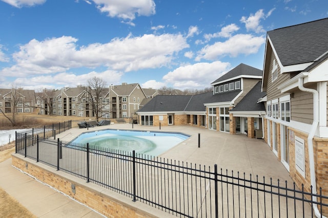 community pool featuring a residential view, a patio, and fence