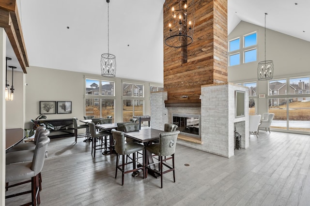 dining space featuring hardwood / wood-style floors, high vaulted ceiling, a fireplace, and a chandelier