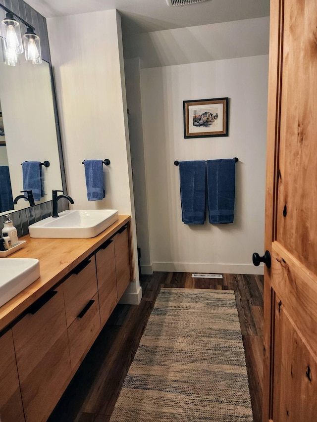 bathroom with double vanity, a sink, baseboards, and wood finished floors