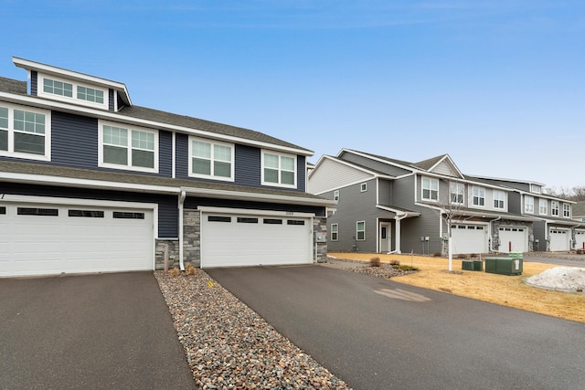 view of front of house with central AC unit, stone siding, a residential view, aphalt driveway, and an attached garage