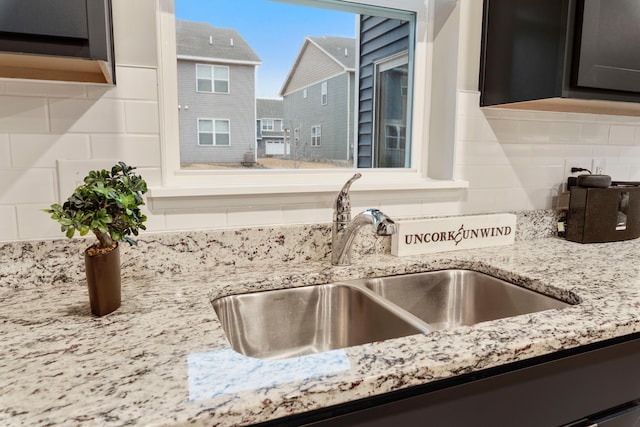 details featuring light stone counters, decorative backsplash, and a sink