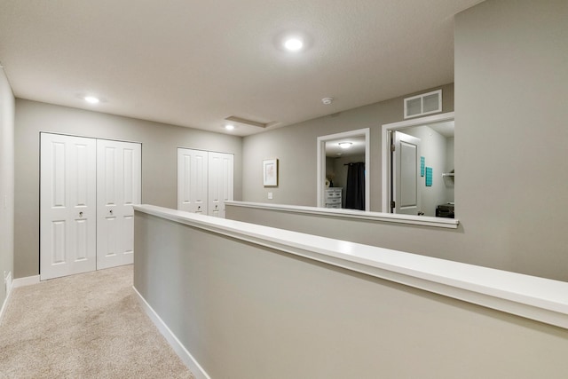 corridor with recessed lighting, carpet flooring, an upstairs landing, visible vents, and baseboards