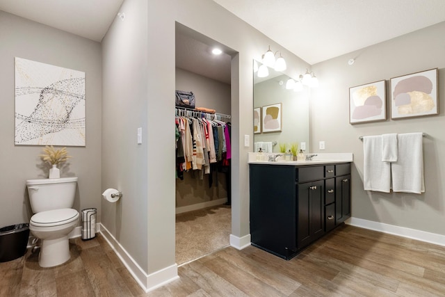 bathroom featuring baseboards, vanity, toilet, and wood finished floors