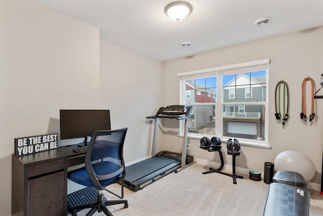 workout area featuring a textured ceiling, carpet, and baseboards