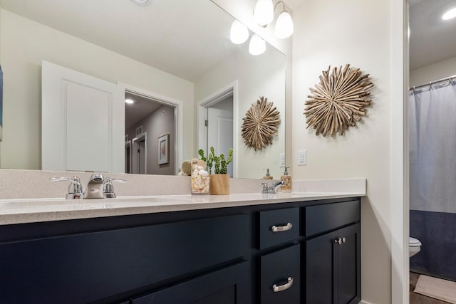 full bath featuring double vanity, a sink, and toilet