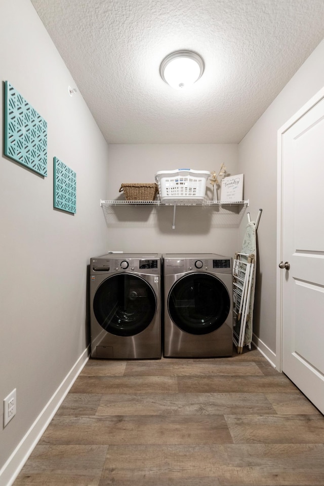 washroom featuring a textured ceiling, laundry area, separate washer and dryer, and wood finished floors