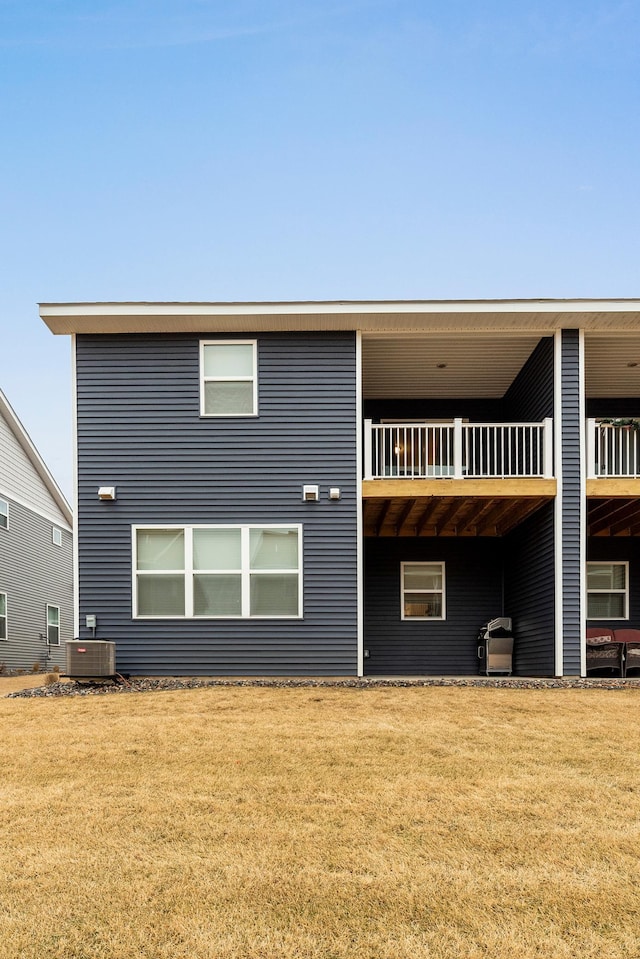 back of house featuring central AC, a lawn, and a balcony