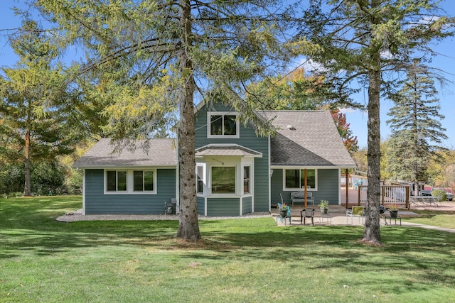 view of front of house with a patio, a shingled roof, and a front yard