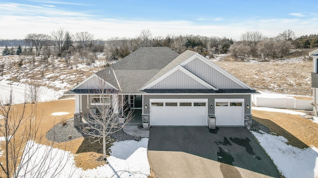 view of front facade with aphalt driveway, stone siding, fence, and an attached garage