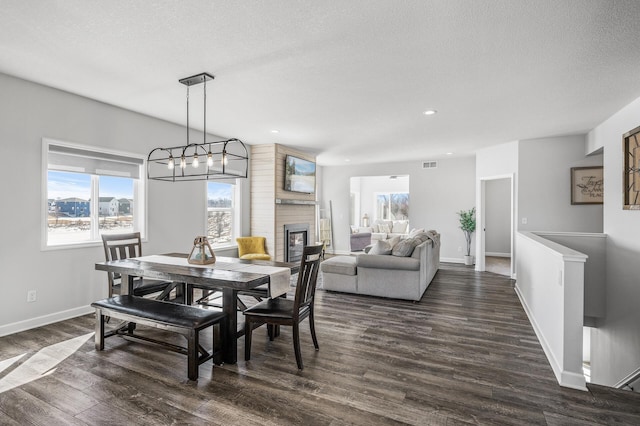 dining space with visible vents, dark wood-type flooring, a brick fireplace, a textured ceiling, and baseboards