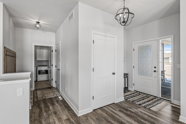 foyer with baseboards, visible vents, dark wood finished floors, and a notable chandelier