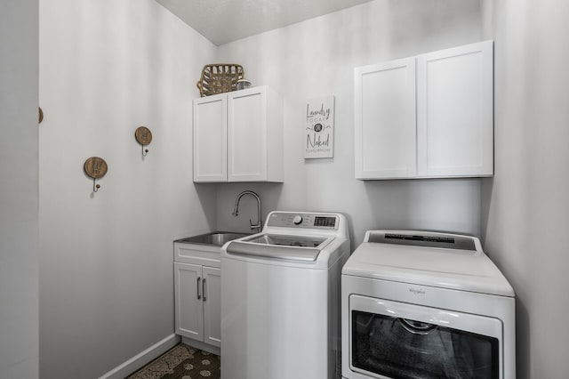 laundry area with baseboards, cabinet space, a sink, and washing machine and clothes dryer